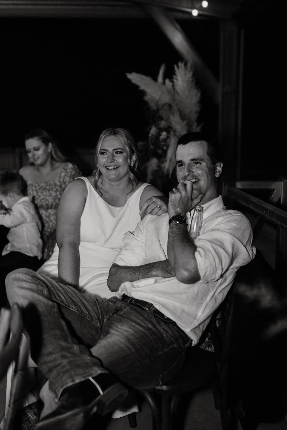 Newlyweds laughing together during their reception speeches