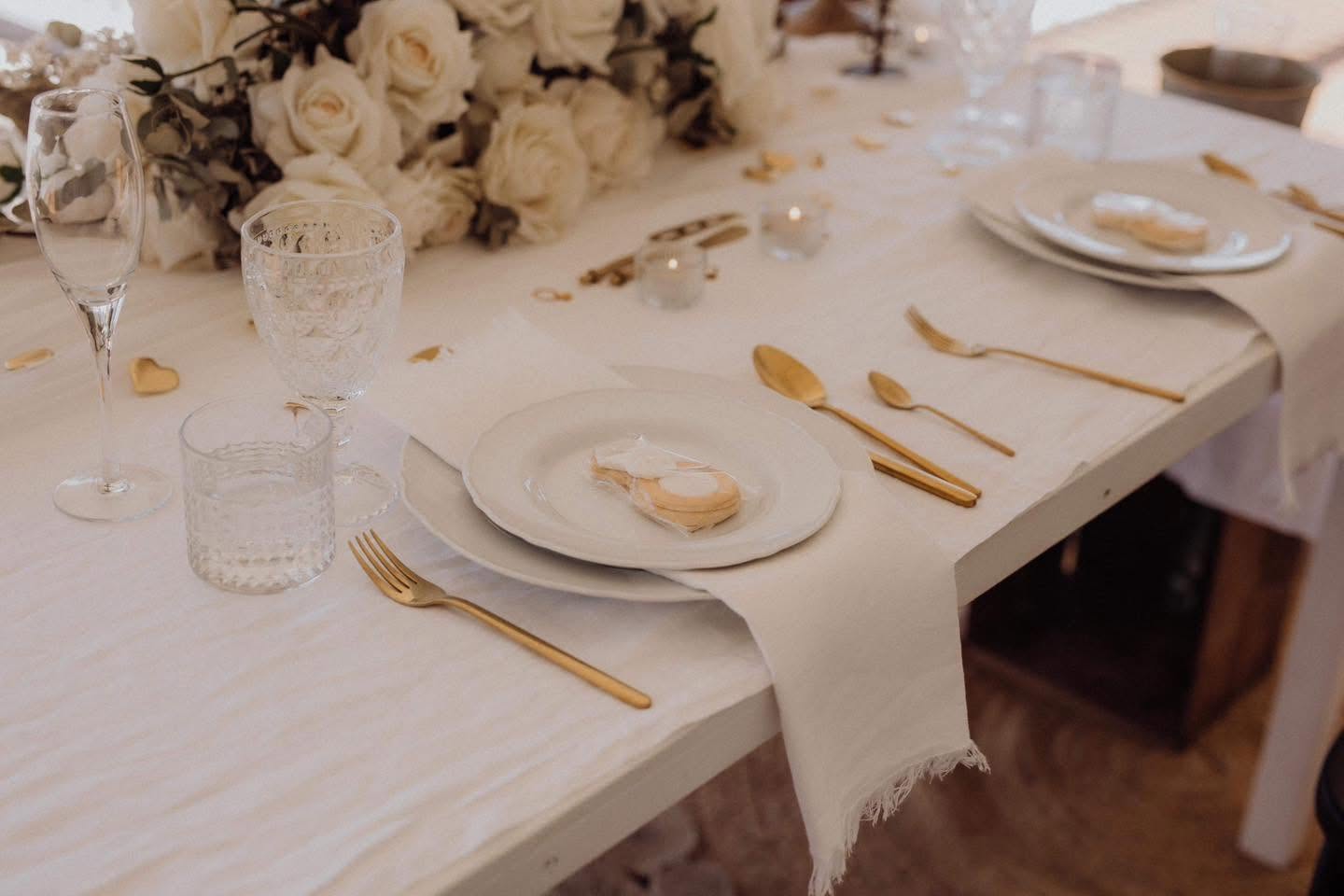 Styled reception table with gold cutlery and white roses